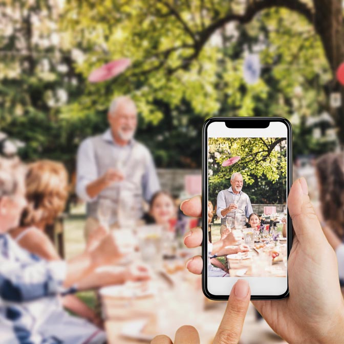 Frau macht Foto von Feier und speichert diese via Handy direkt im digitalen Fotoalbum auf sendmoments.de
